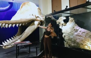 Luz Poulard, egresada de Biología Marina UC posando frente a dos fósiles marinos en Perú