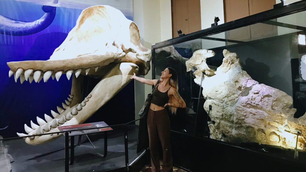 Luz Poulard, egresada de Biología Marina UC posando frente a dos fósiles marinos en Perú